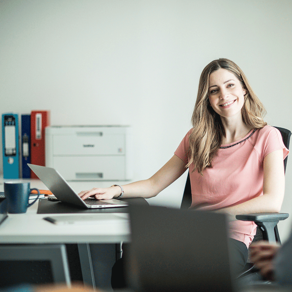 Woman sat at desk smiling with HLL3210CW on desk