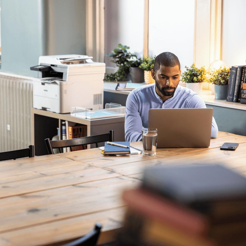 Brother MFC-L3740CDW LED printer in an office environment with a man using a laptop in the foreground