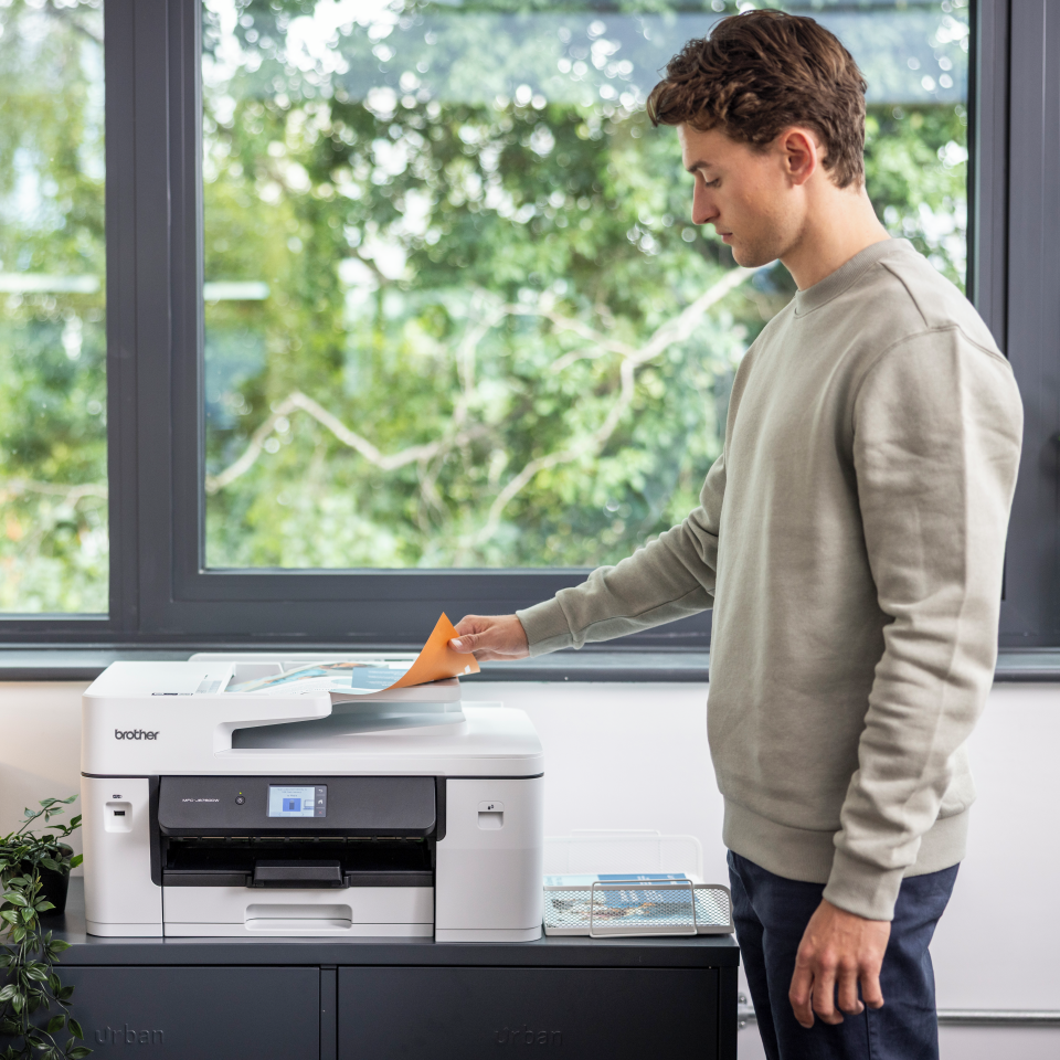 <p>Man taking A3 output from an inkjet printer</p>