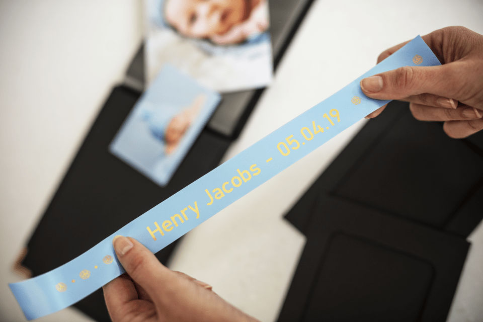 Brother TZe-RL54 satin ribbon tape cassette - gold on light blue - new born baby photo album with the name and date of birth of the baby