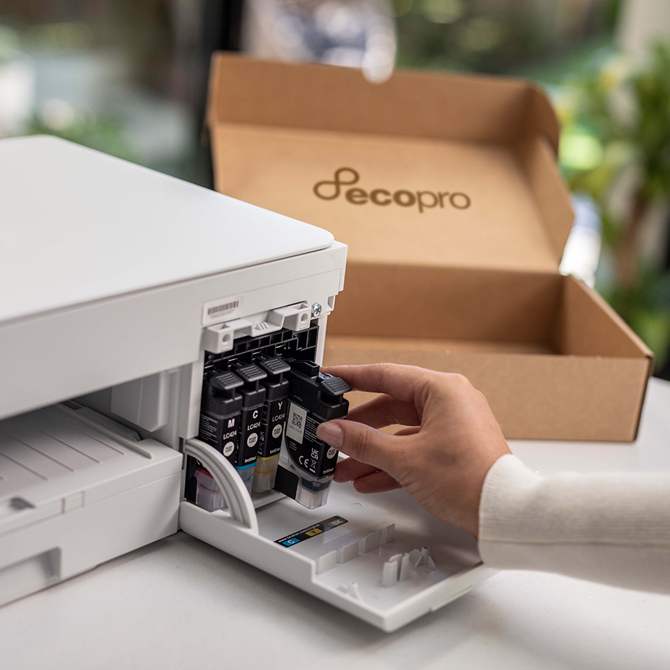 woman's hand inserting an ink cartridge into the DCP-J1200WE, EcoPro cardboard box in the background. 