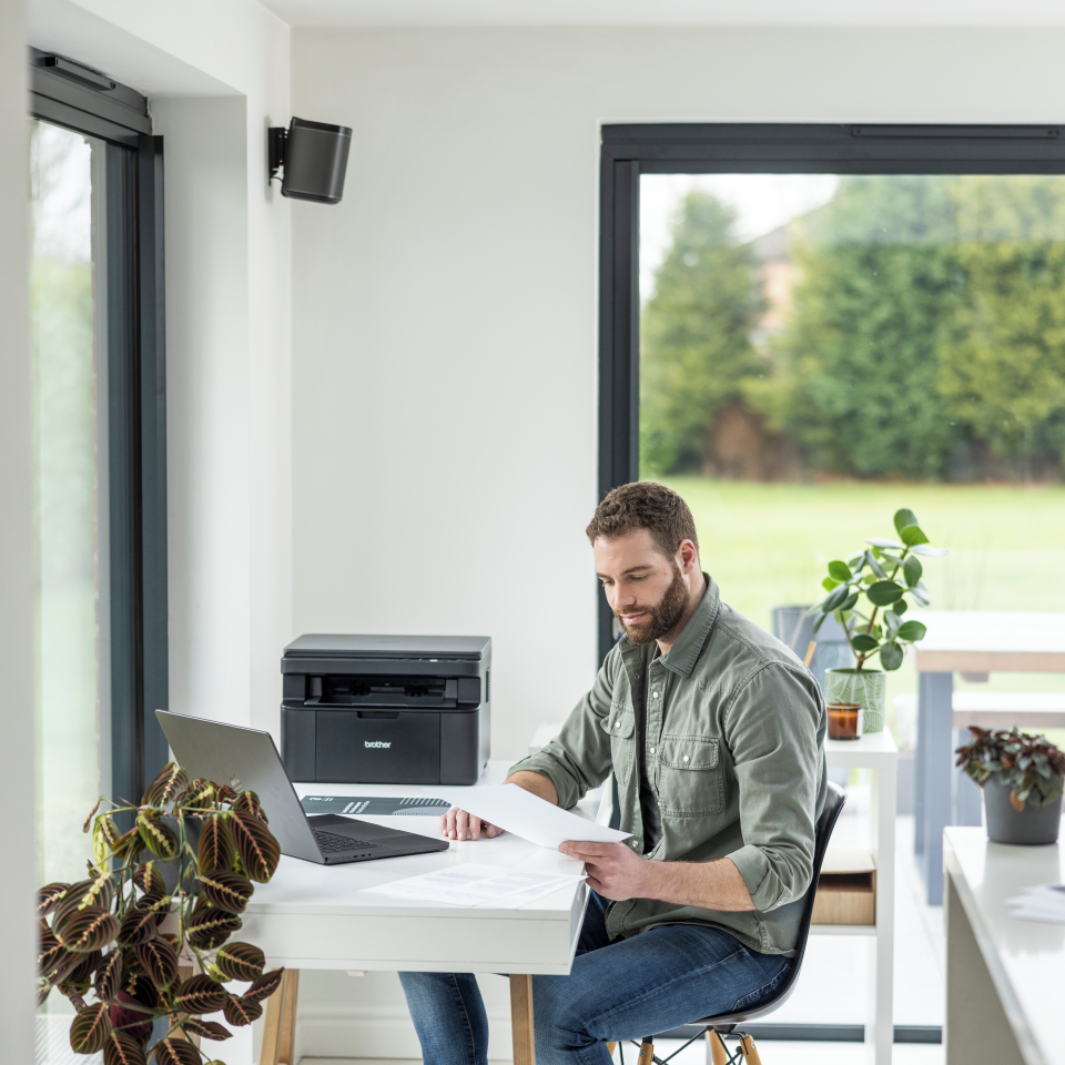 <p>Man reviewing output taken from the DCPL1640W mono laser printer</p>