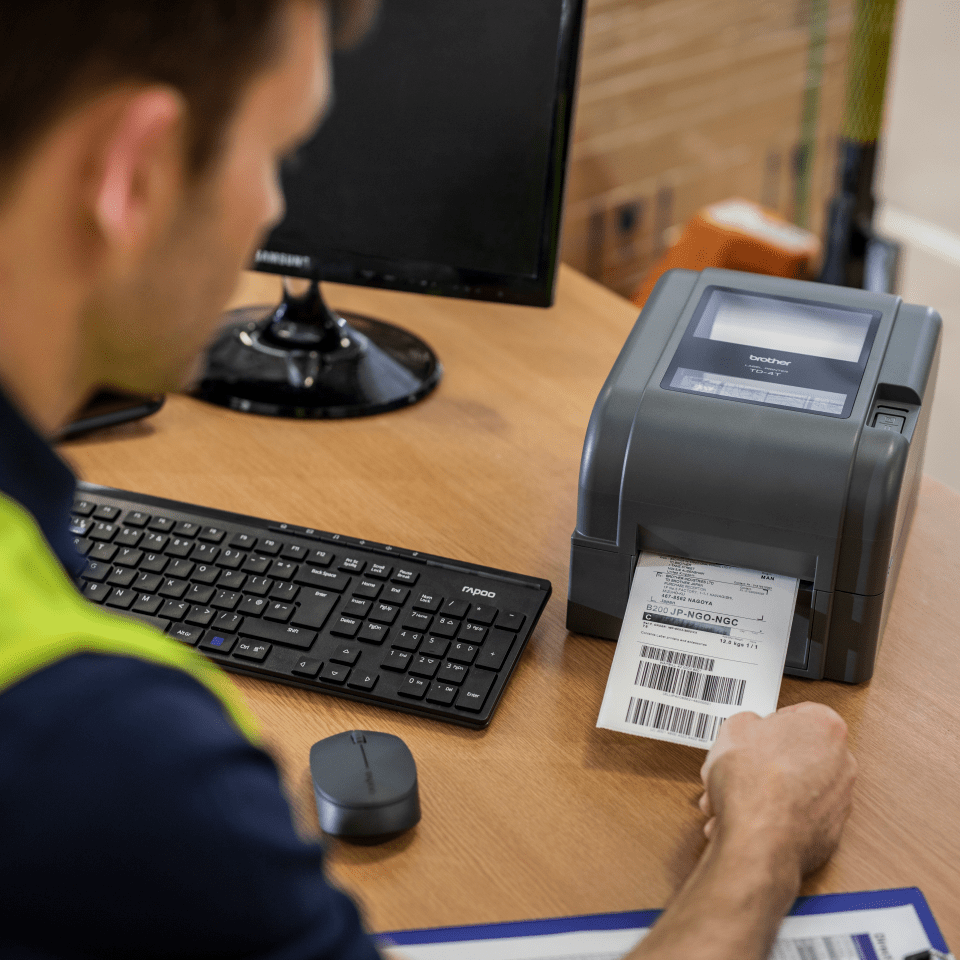 Warehouse operative printing shipping label with barcodes on Brother thermal transfer label printer