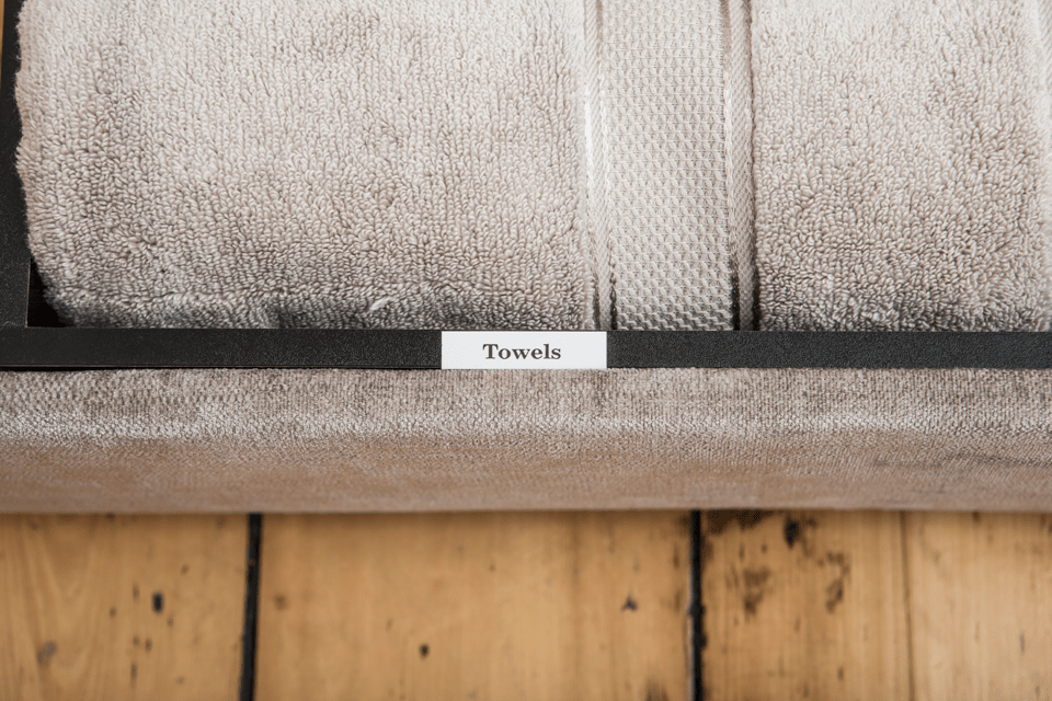 Brother TZe-241 non-laminated tape cassette - black on white - shelf in a bathroom labelled "Towels" 