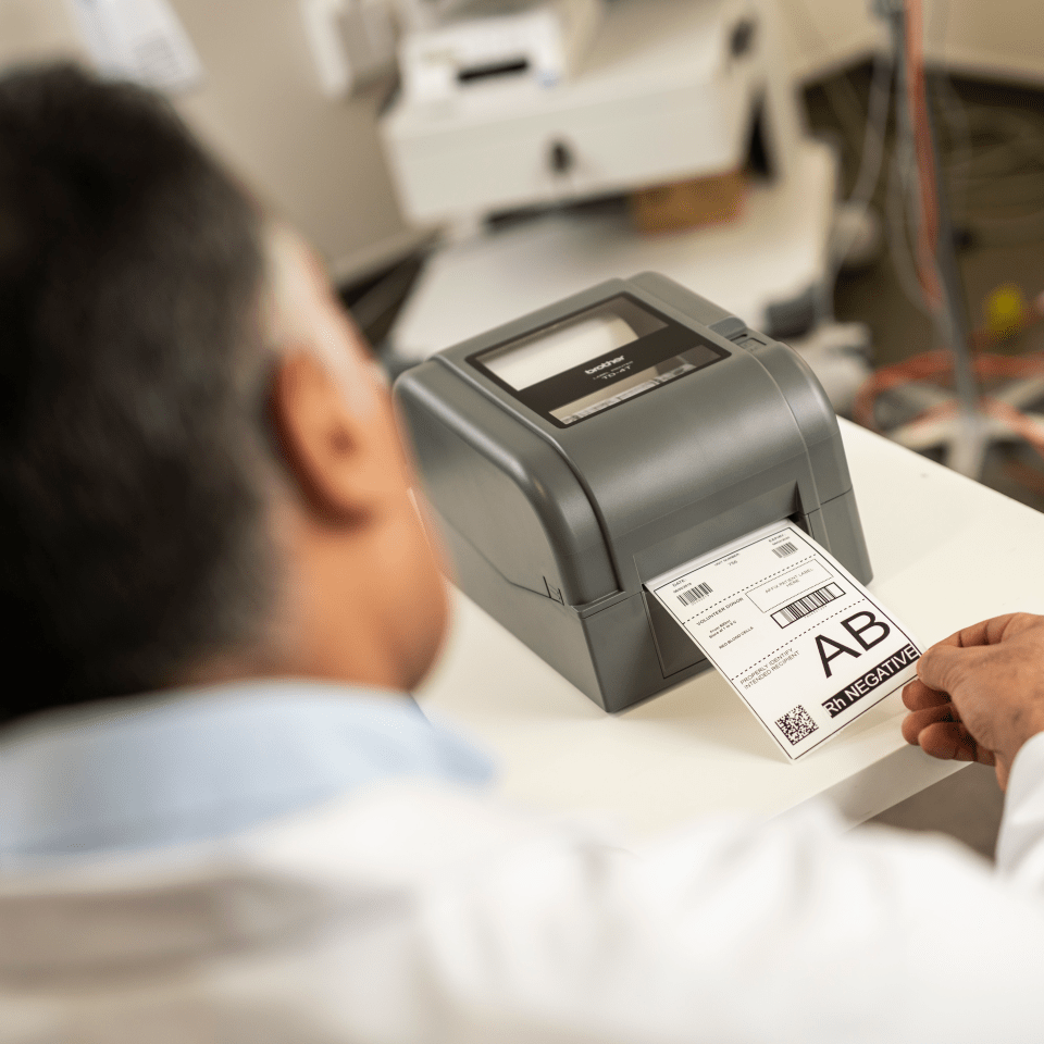 Doctor, clinician or laboratory assistant printing a blood bag label on a Brother thermal transfer label printer