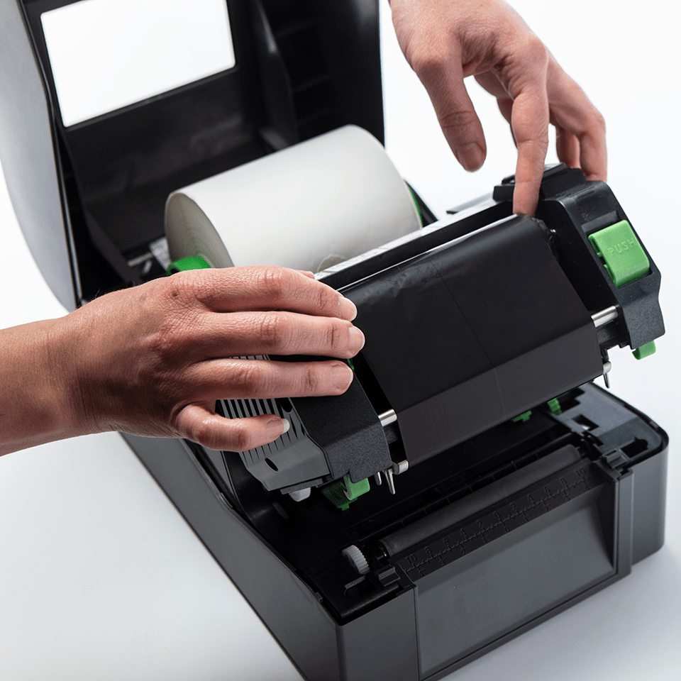 Hands setting up black thermal transfer ribbon in TD label printer