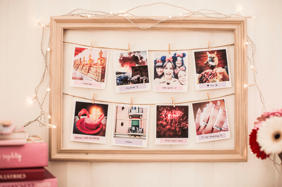 Eight Polaroid photos labelled and pegged to two lines of string within a picture frame