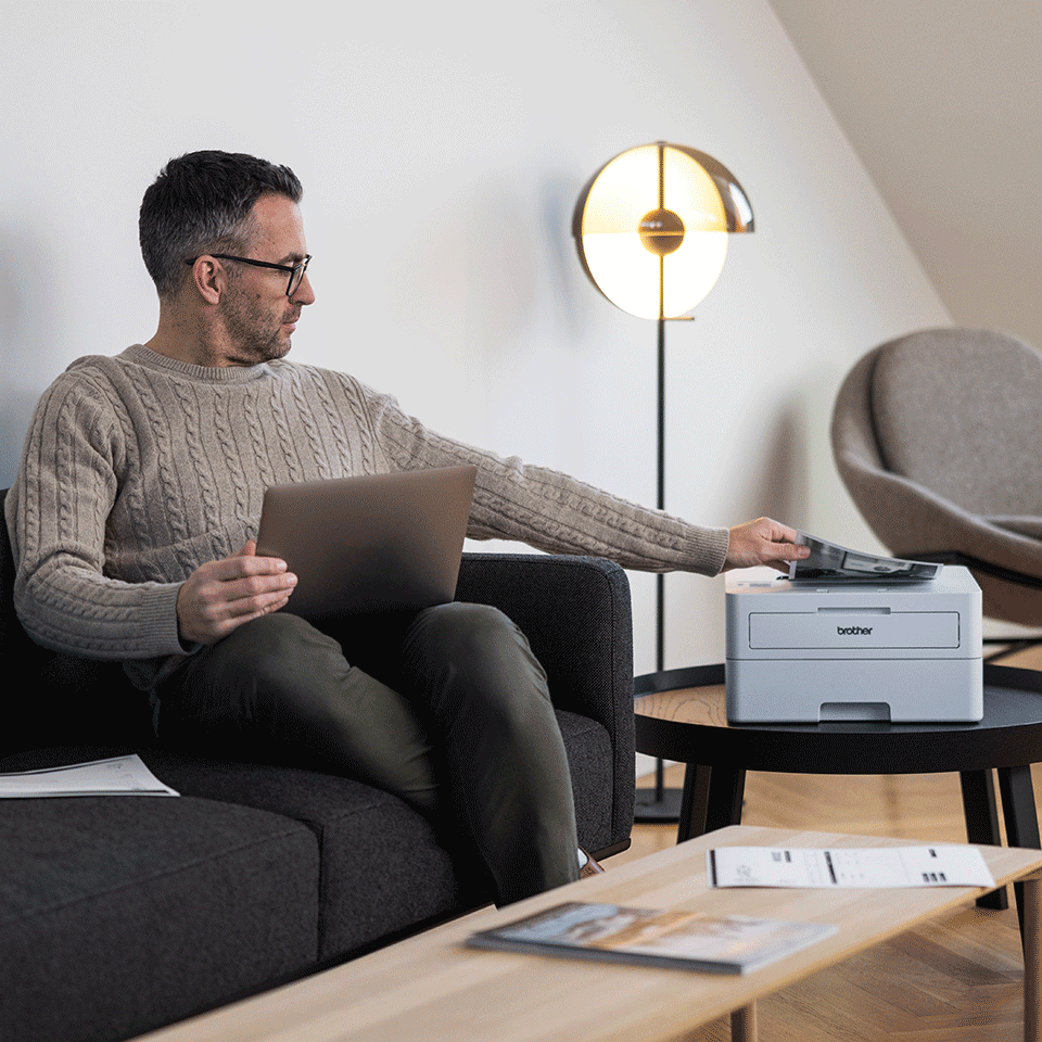 Man sat on sofa using Brother HL-L2865DW