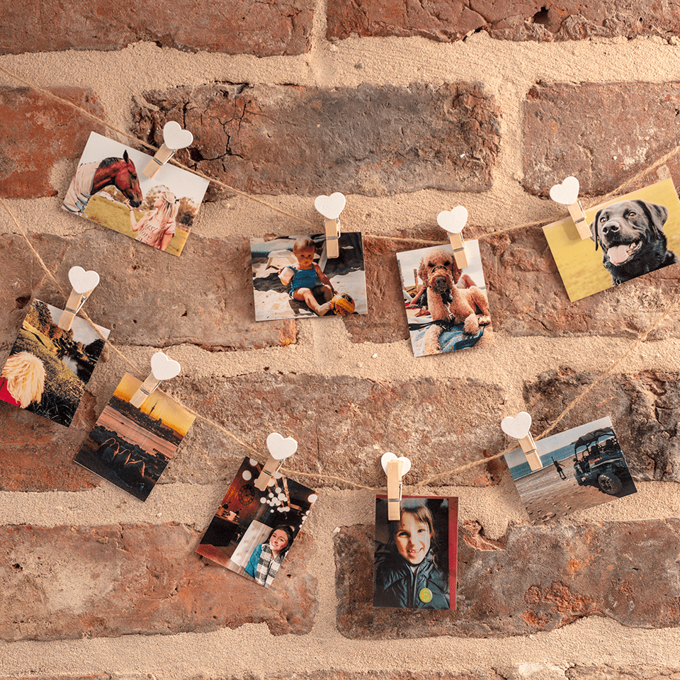 Various photographs pegged along string against a brick wall