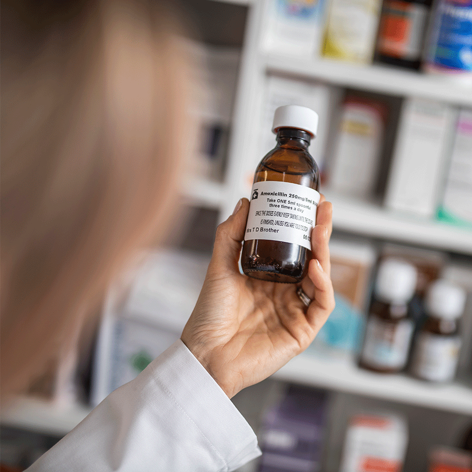 Female pharmacist putting label on medication