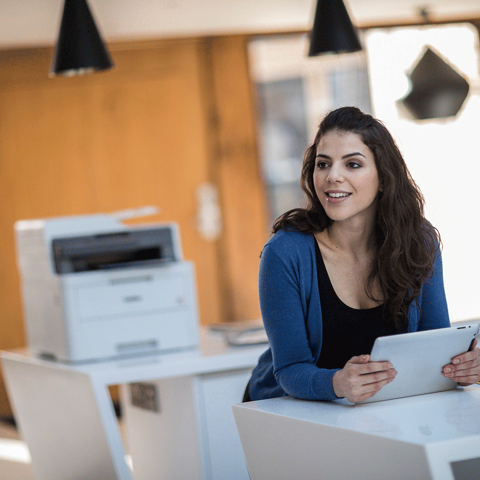 Woman using tablet with DCPL3510CDW in background