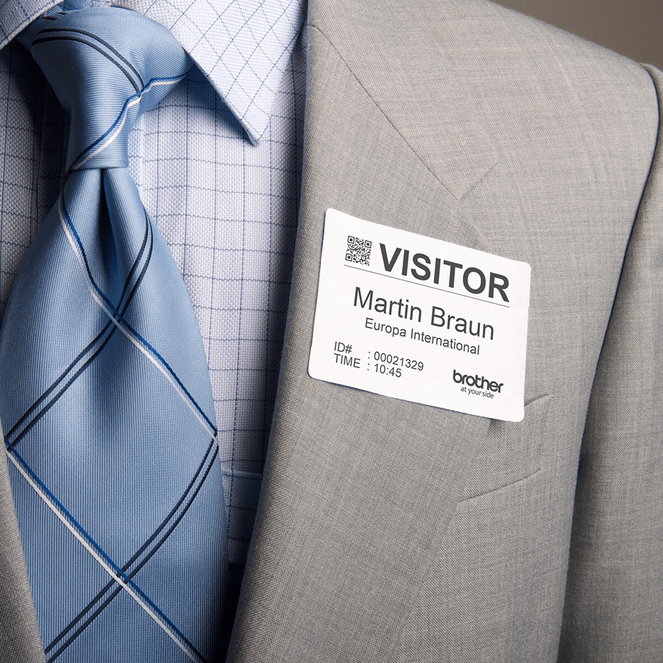 Man wearing a blue tie with a DK-11234 adhesive visitor badge label directly stuck to his suit