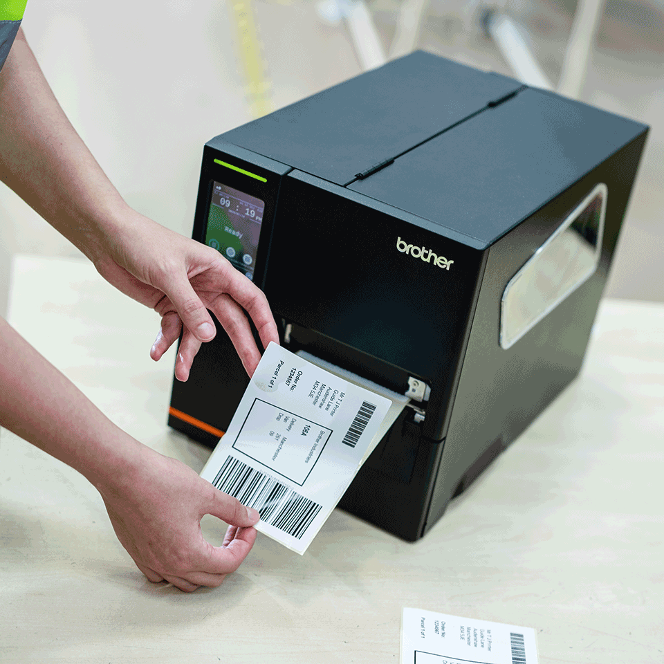 A person removing a printed label from a Brother industrial label printer
