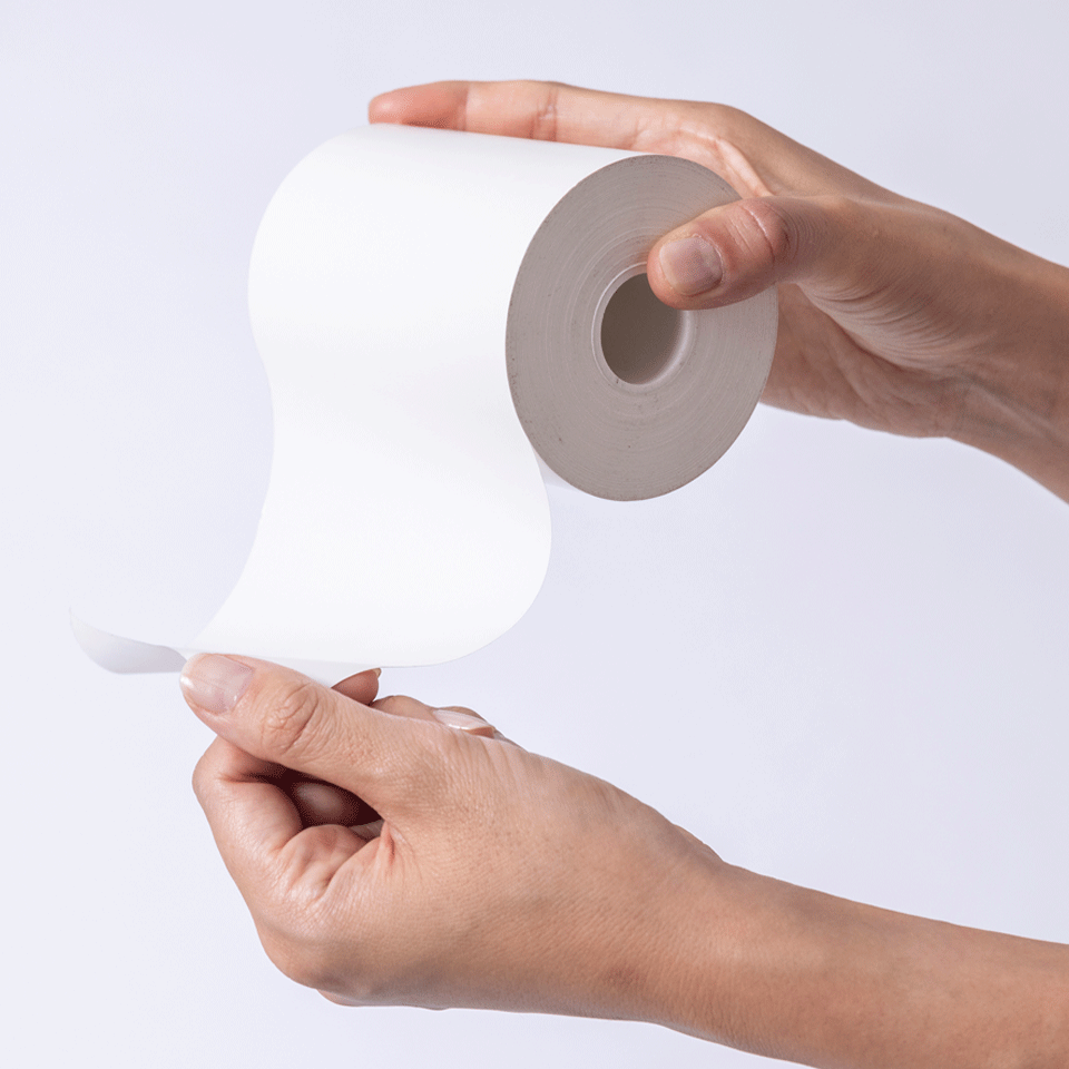 <p>A hand holding the 4" linerless labels for Brother products. </p>