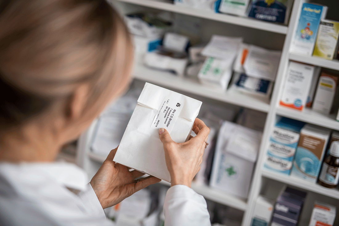 Medicine label being stuck on medicine bag in pharmacy