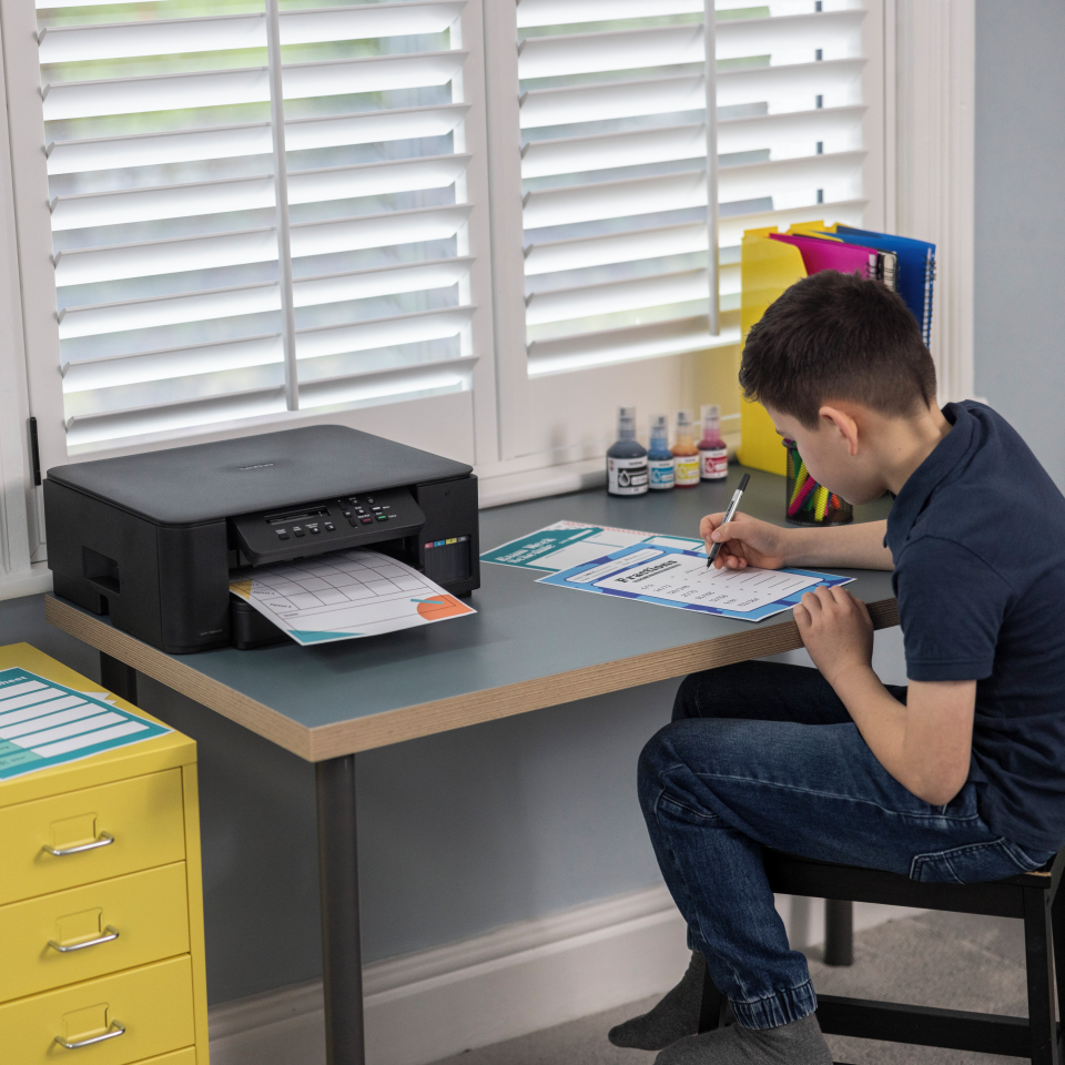 <p>Child working next to Brother printer</p>