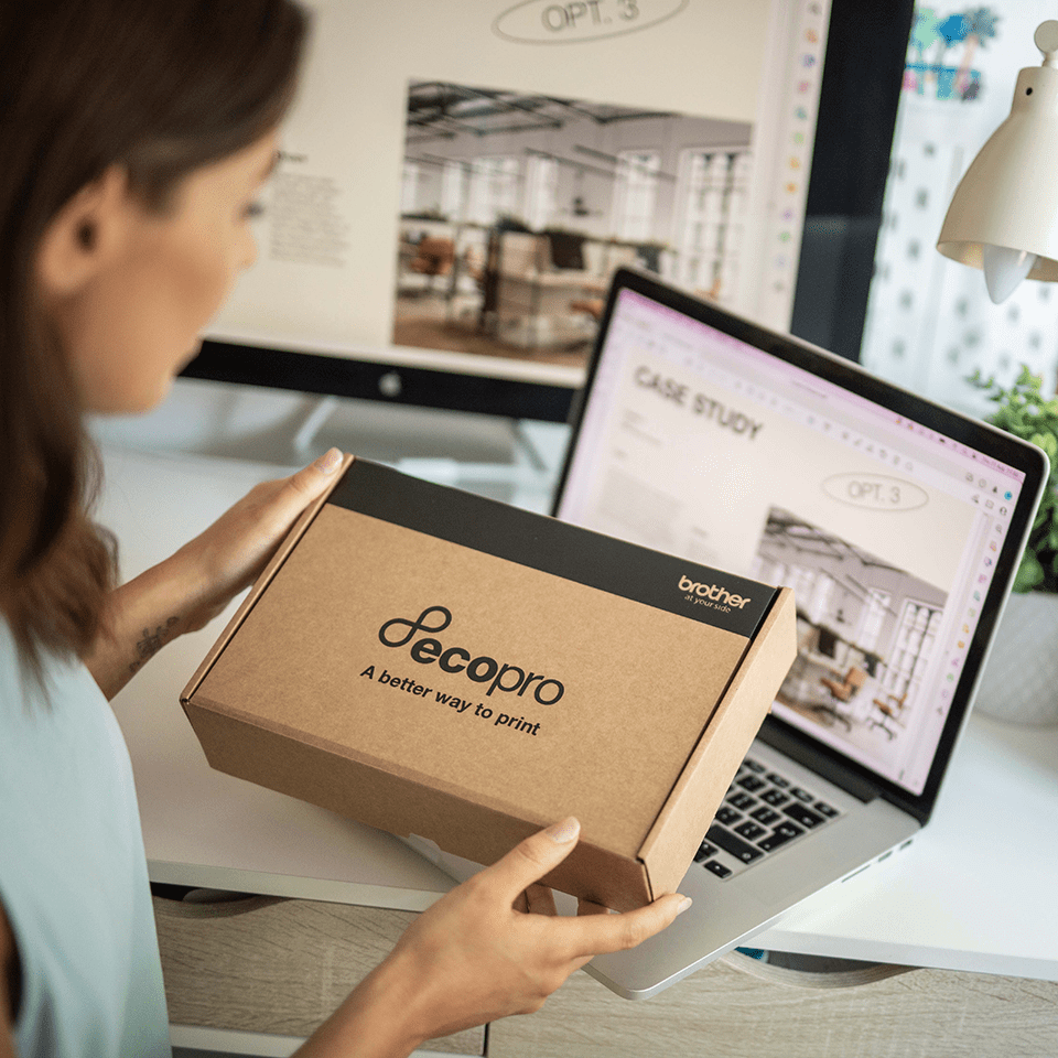 Woman sat at her laptop holding a cardboard EcoPro box