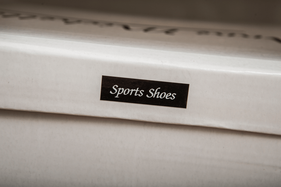Brother TZe-335 label tape cassette - white on black - shoe box labelled with "sports shoes" identifying the contents of the box 