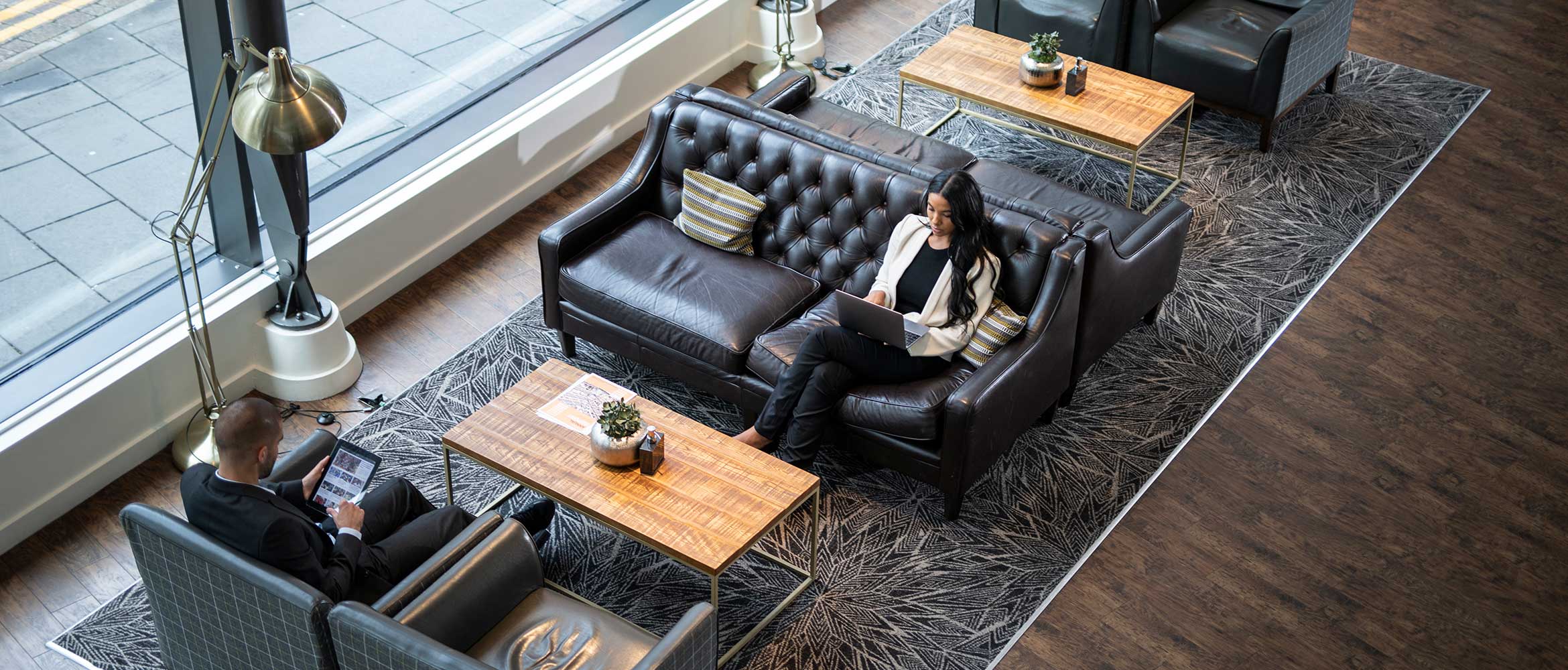 Two people sat on sofas with laptops and a table