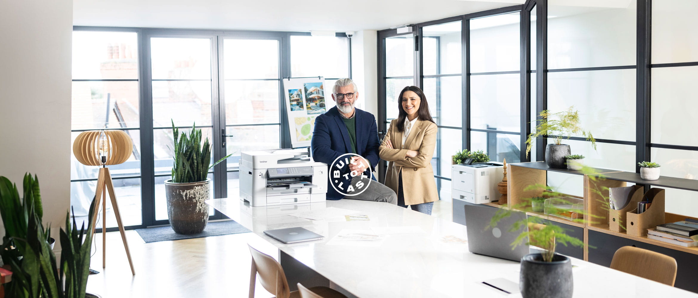 Man and woman stood in an office next to a Brother printer