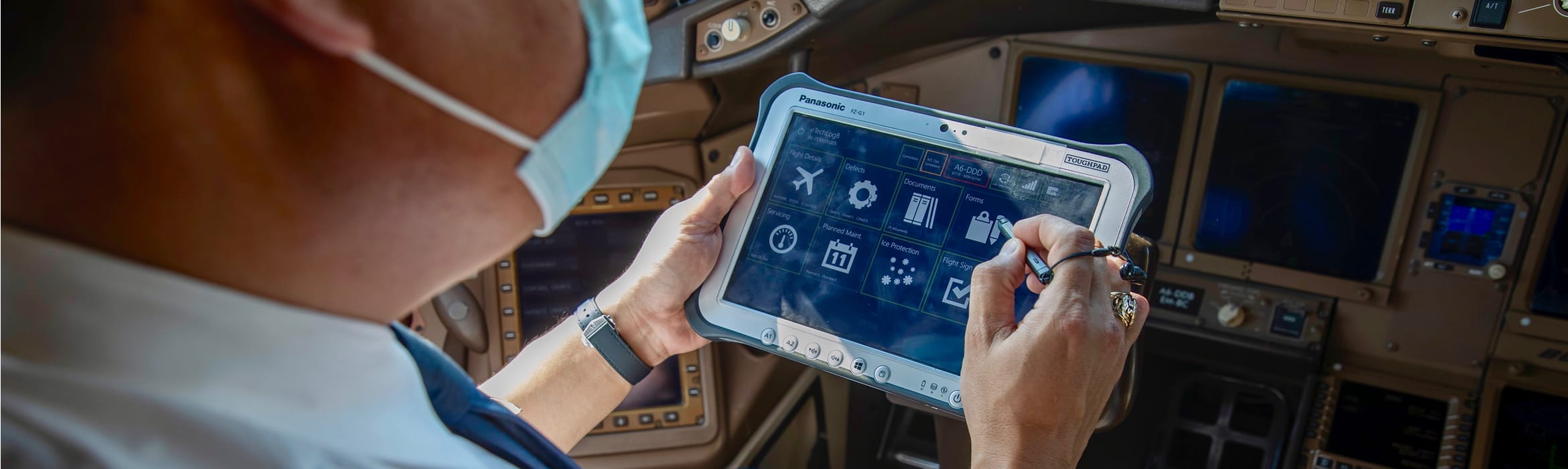 A male pilot using an eTechLog8 tablet to log safety checks while sitting in an aircraft cockpit