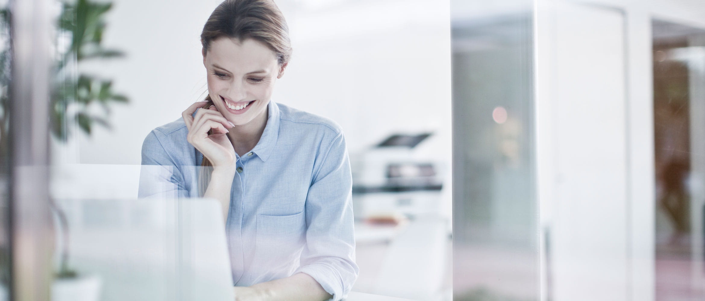 Business woman looking down at laptop while smiling