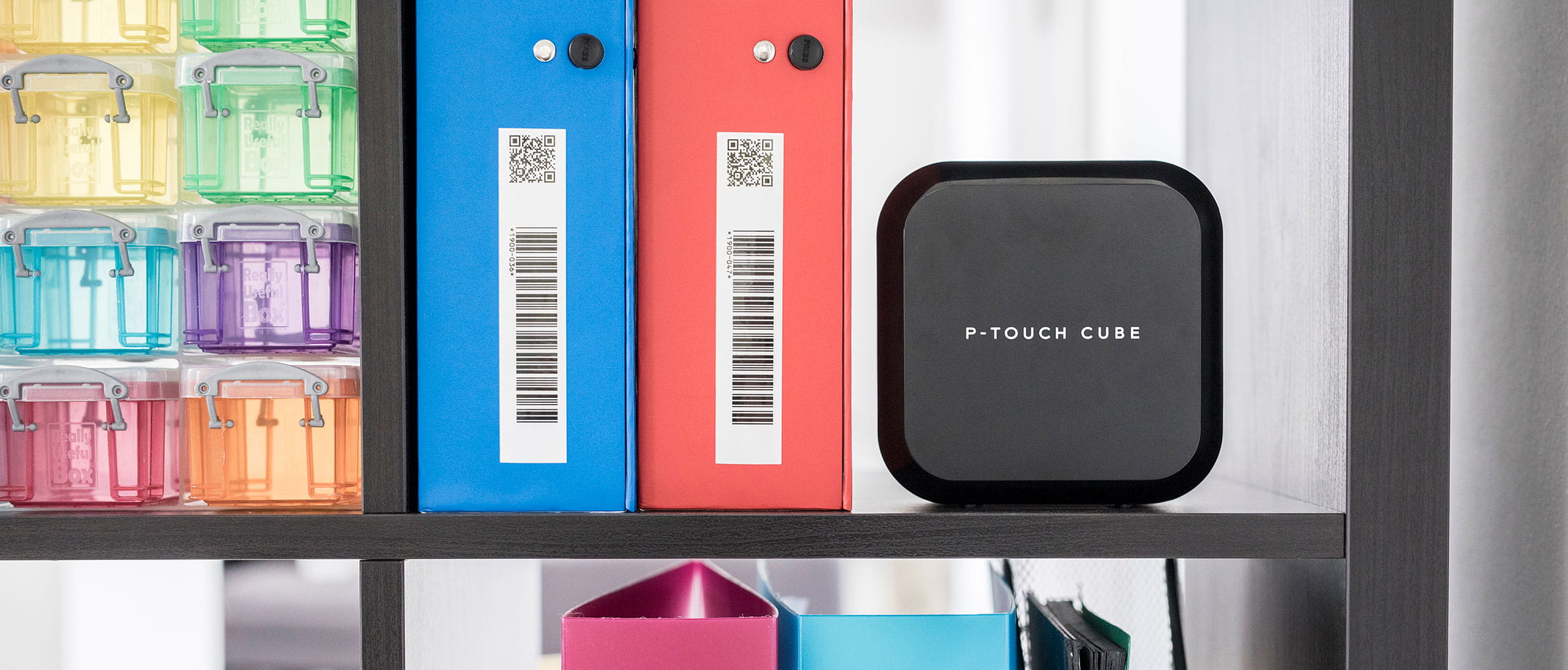 A Brother P-touch címkenyomtató polcon, vonalkódokkal ellátott címkézett mappák mellett