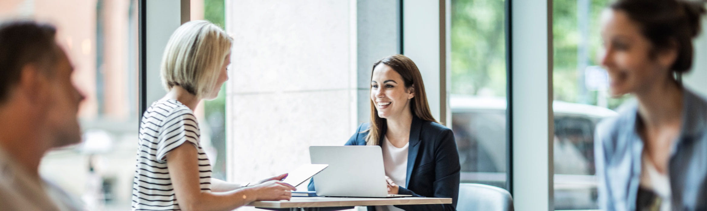 Two ladies chatting at a desk with a laptop