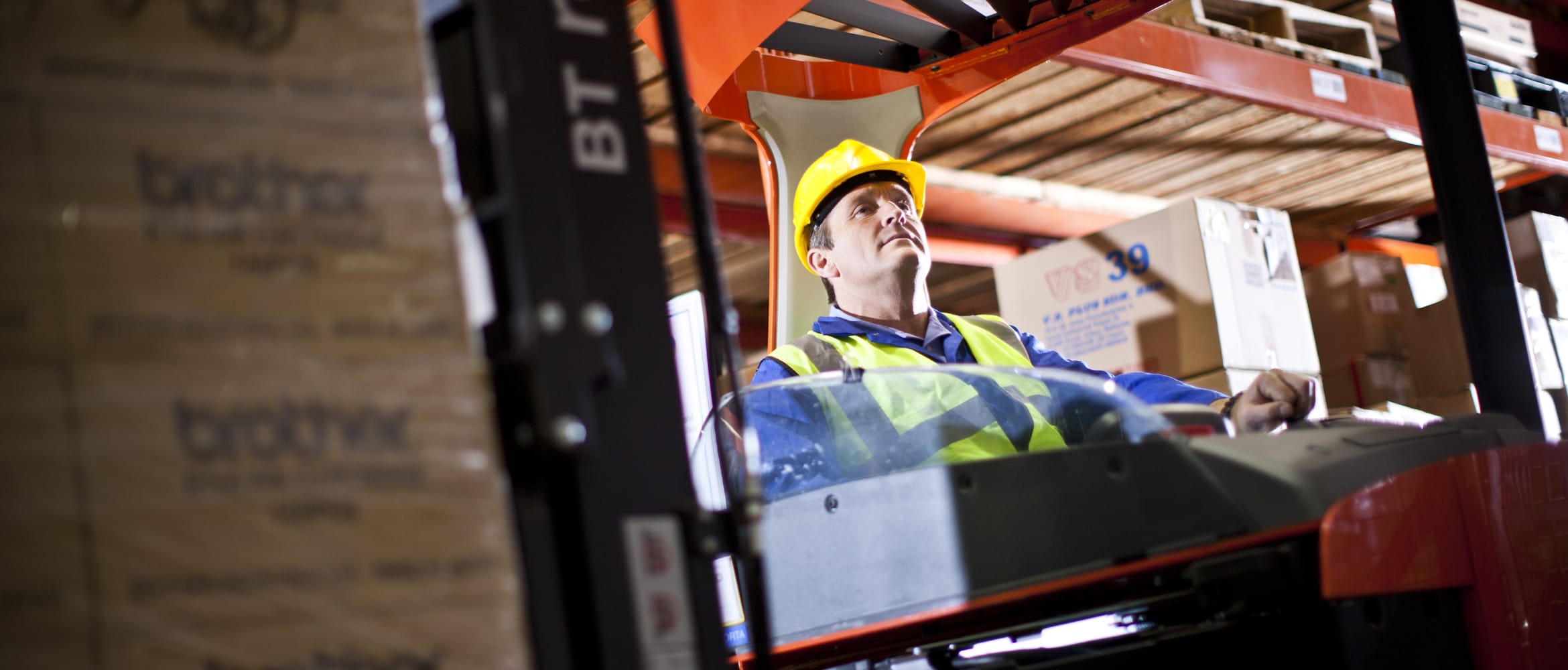 Man with hi-vis jacket and hard hat using forklift truck