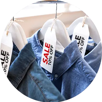 Red and black sale labels on hangers holding denim shirts