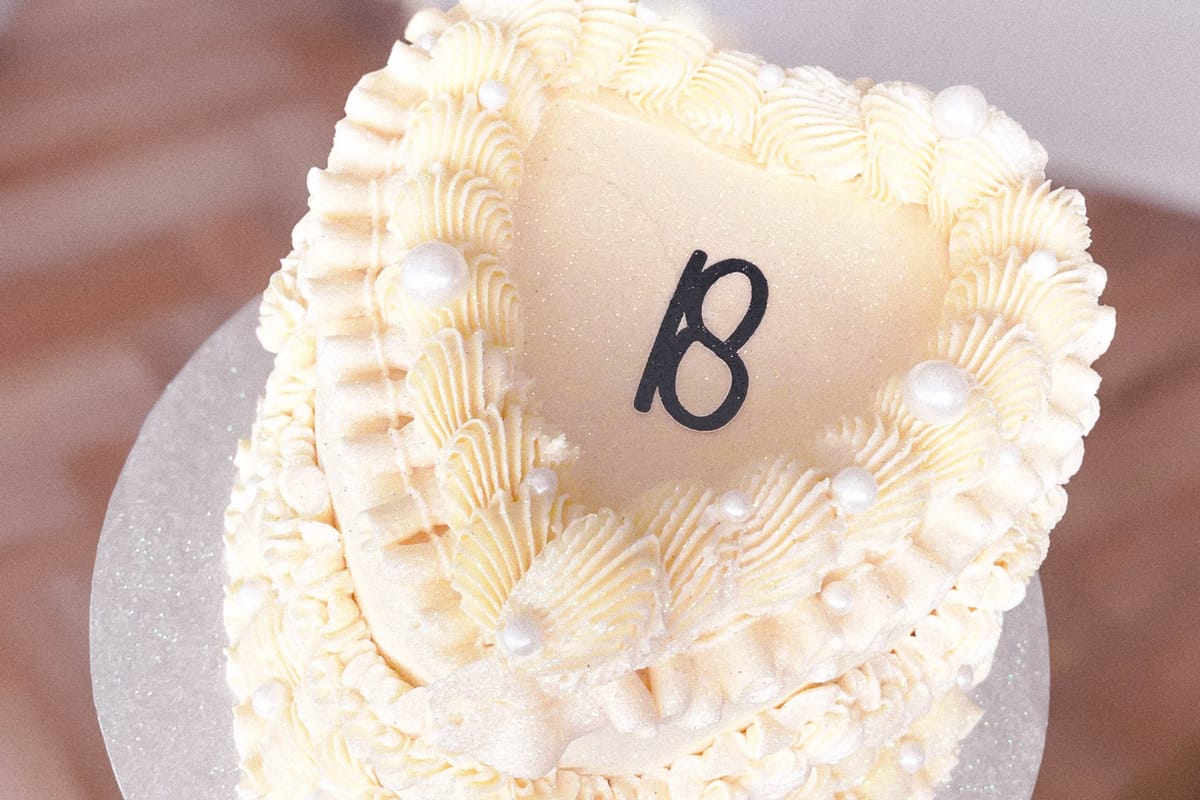 Top view of a heart shaped cake, decorated with cream icing and number 18 on the top