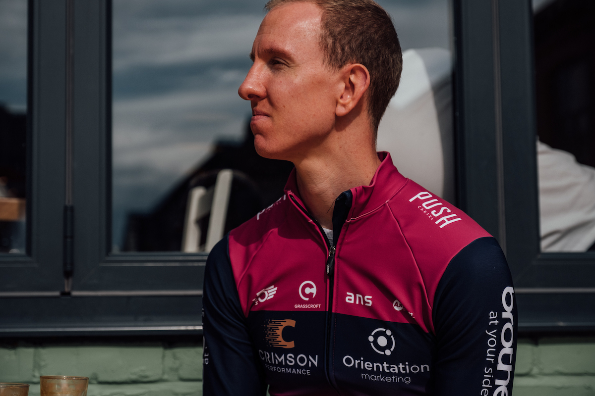Racing cyclist, male, purple and blue jersey, seated, profile view