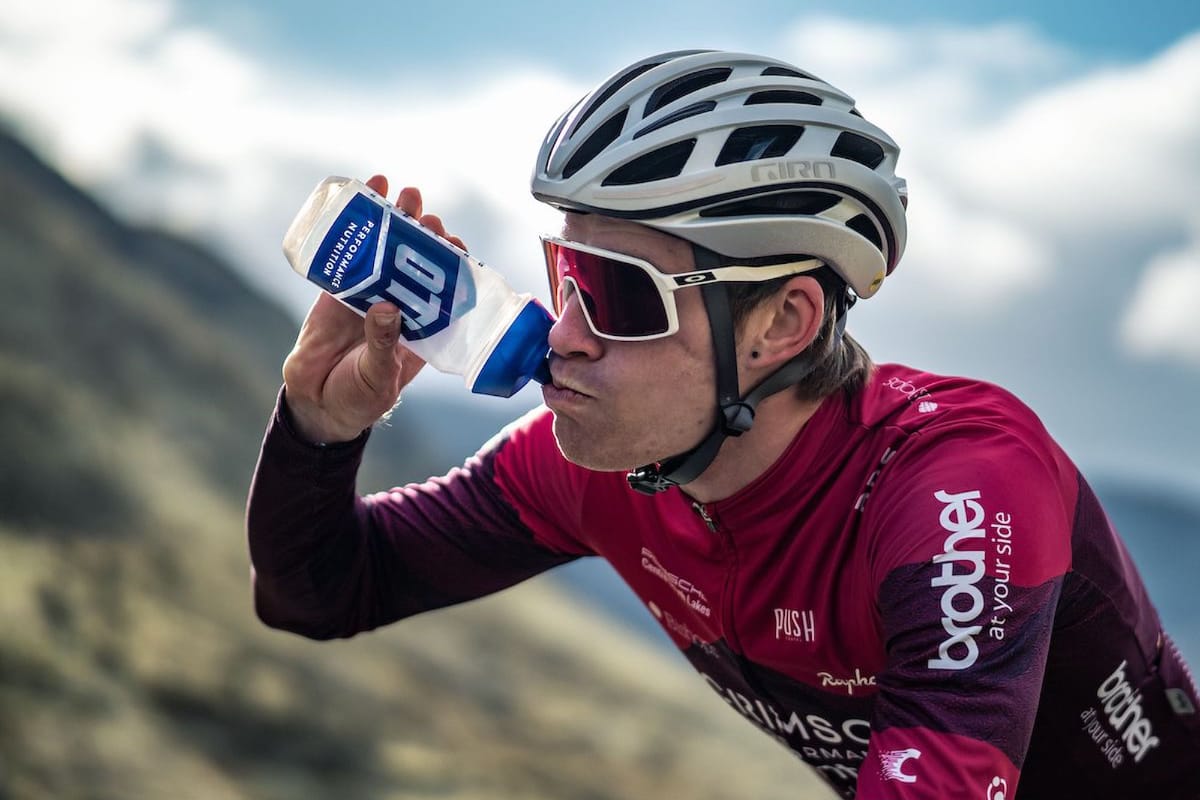 Cyclist Joey Walker rehydrating with greenery and a cloudy sky in the background