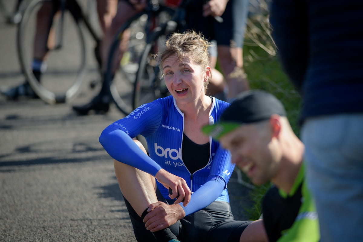 Rebecca Richardson looking exhausted as she sits by the roadside with other cyclists after completing a challenge