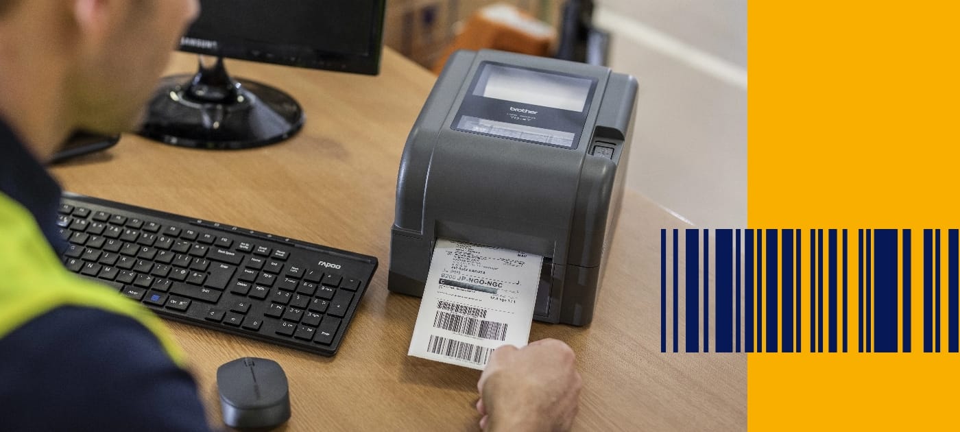 A warehouse worker wearing a high visibility vest removing a barcode label from a Brother TD series label printer