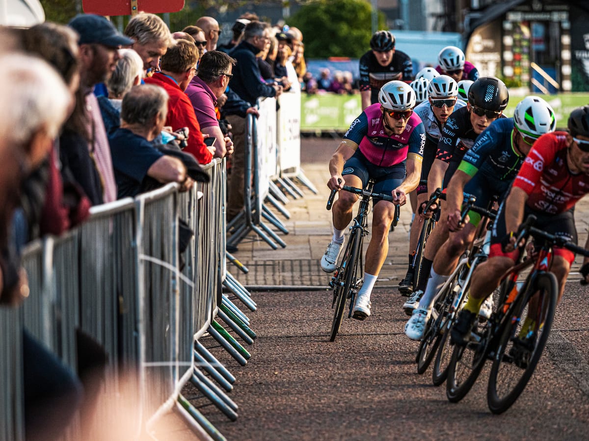 Group of cyclists turning as they pass spectators