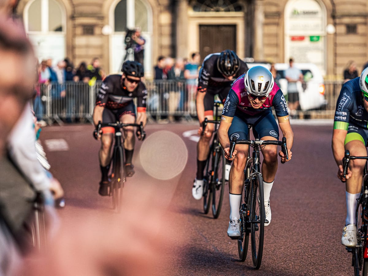 Group of cyclists approaching with spectators in the background and to the side