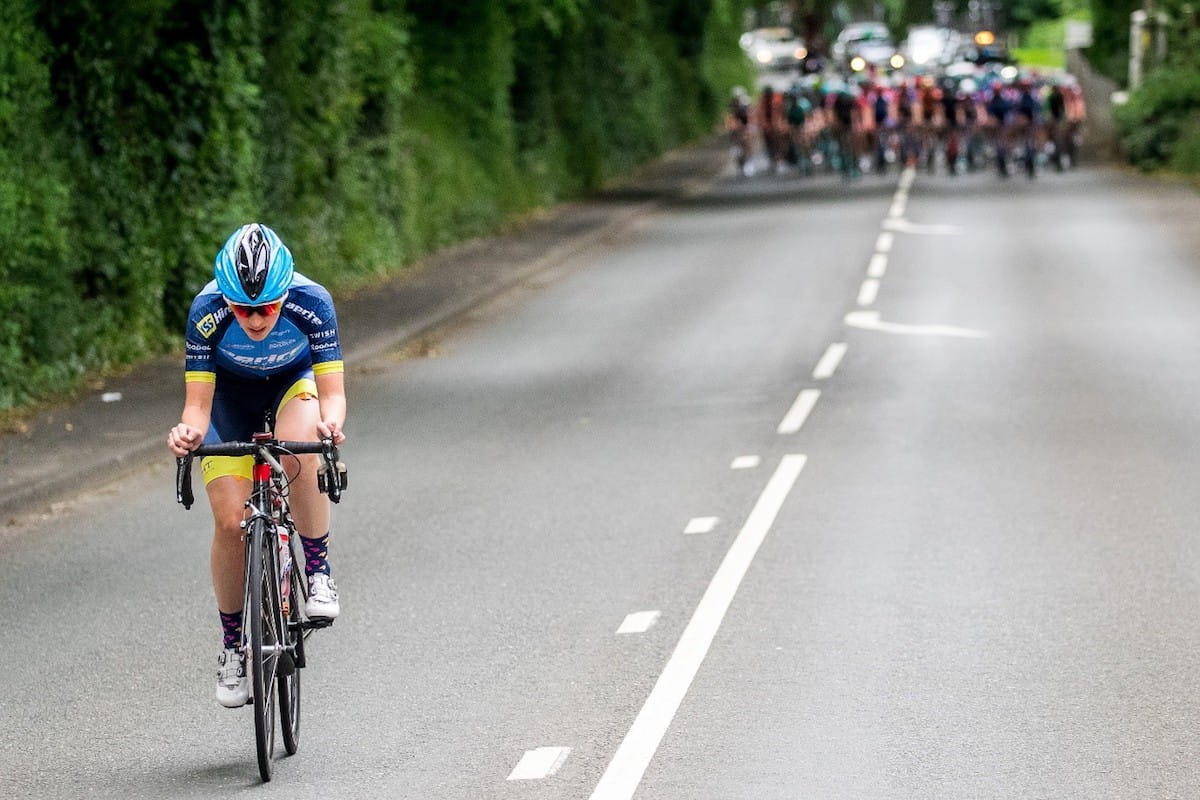 a cyclist leading with the chasing pack advancing in the background