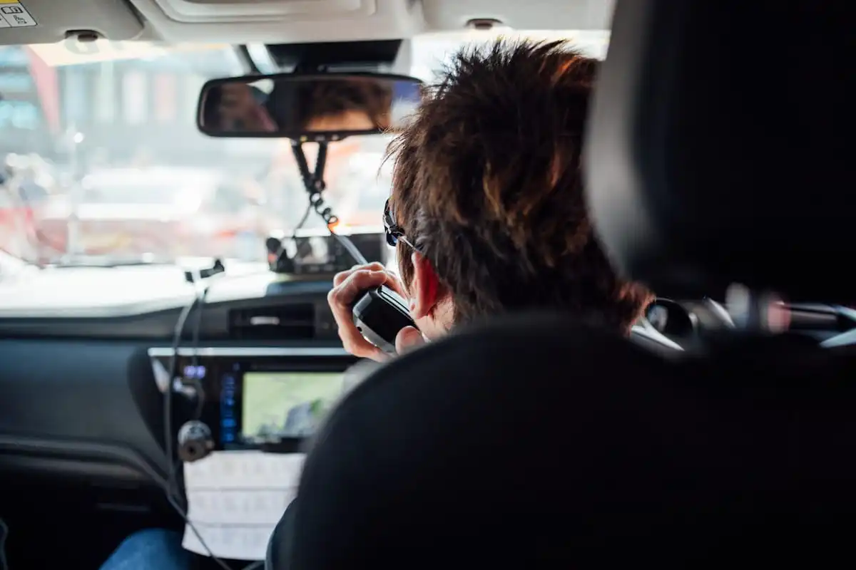 Cherie Pridham talking on a CB radio viewed from the back seat of a cycling team support vehicle