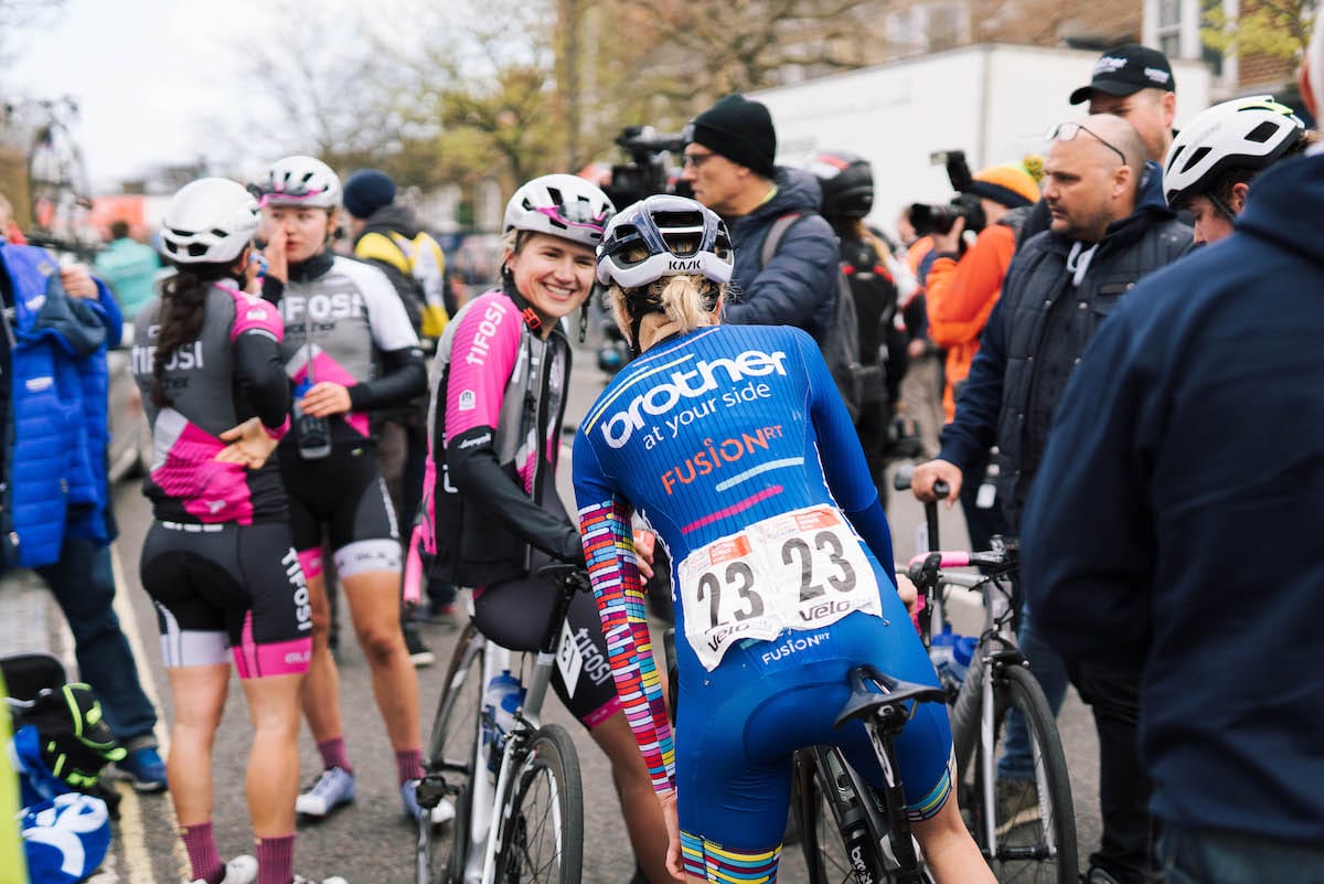 Cyclist from Brother UK-FusionRT team talking to competitor amongst other riders and spectators