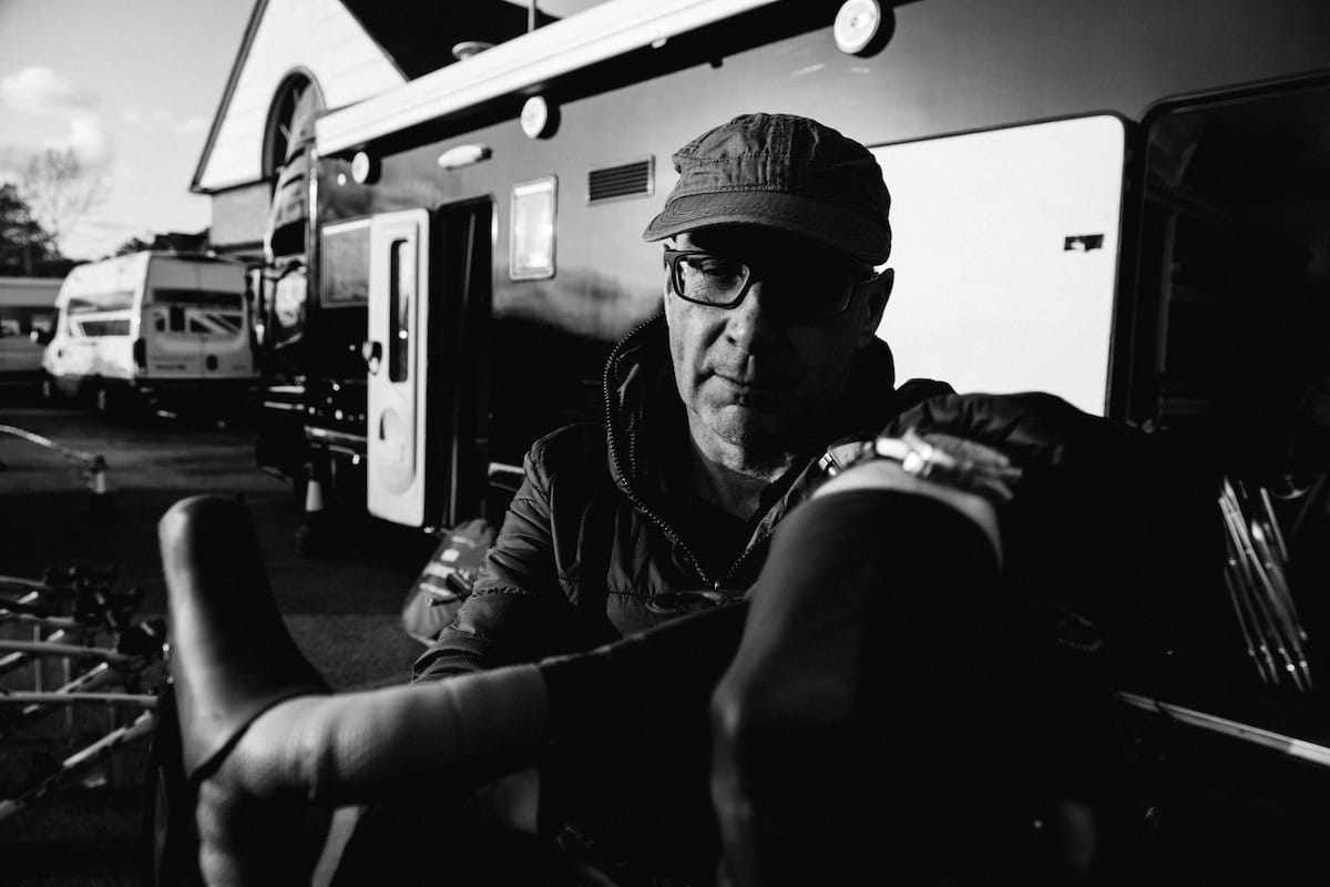 Mechanic Paul Clarke holding the handlebars of a bike in front of a support vehicle in a car park