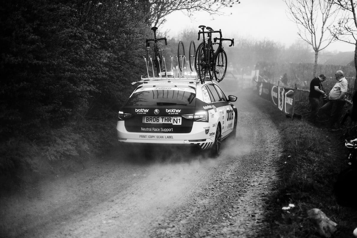 Neutral race support vehicle driving away with spare bikes mounted on roof rack