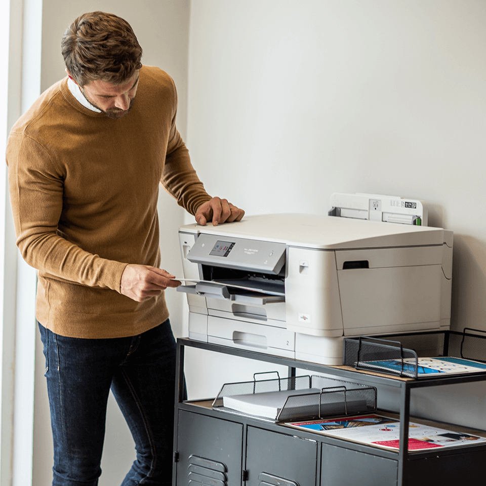 Man in office picking up document from printer