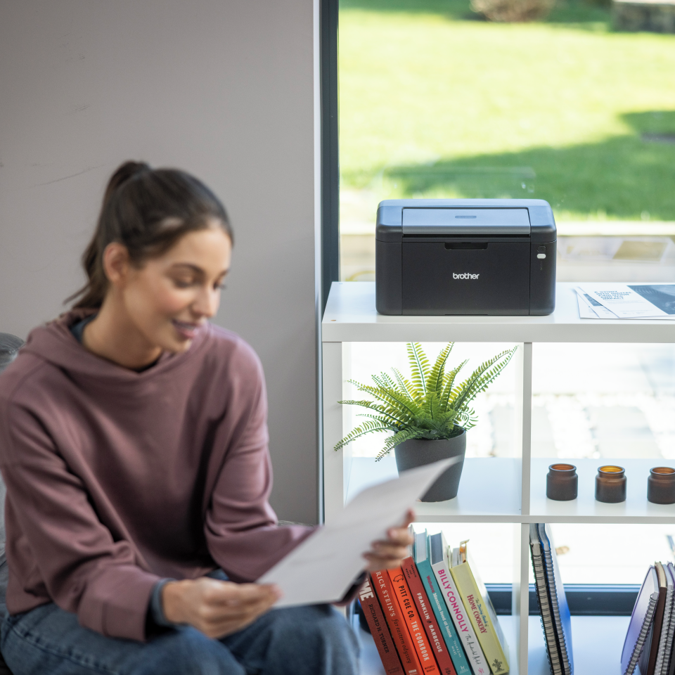 <p>Woman viewing single sided output whilst sat next to the HL-L1240W</p>