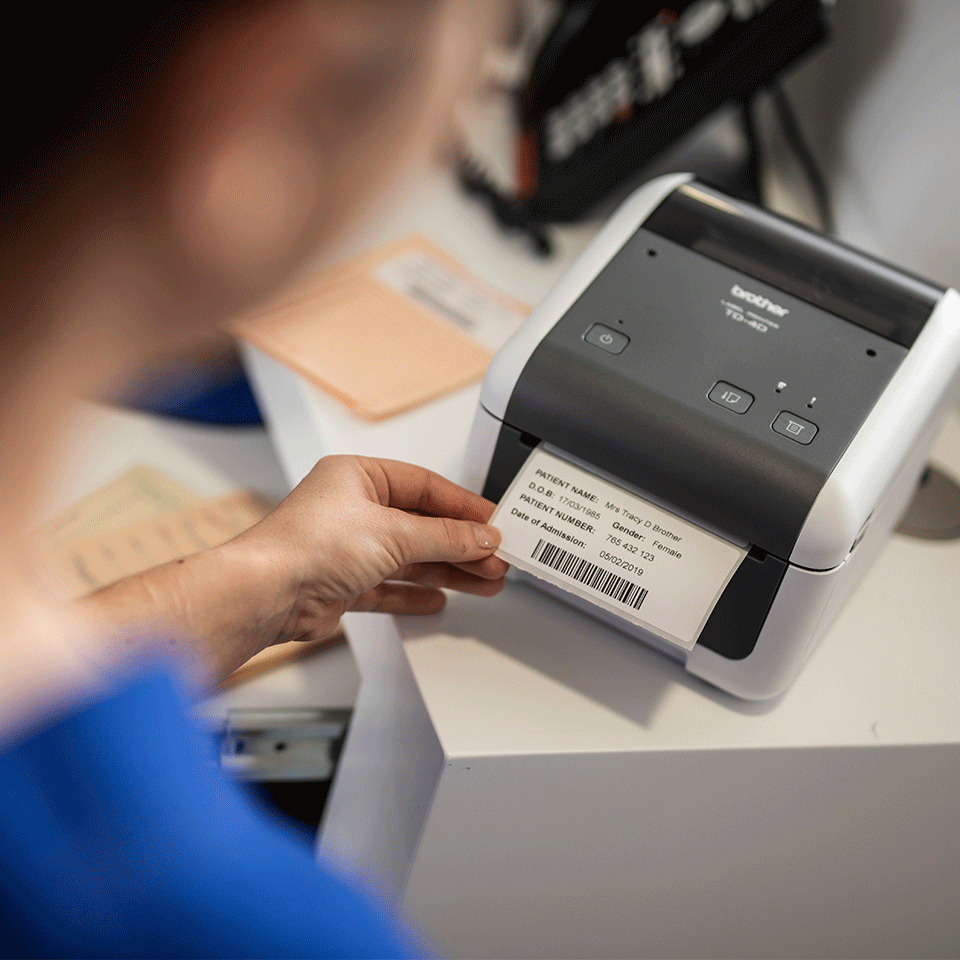 Woman in hospital printing patient information label on Brother TD4520DN desktop label printer
