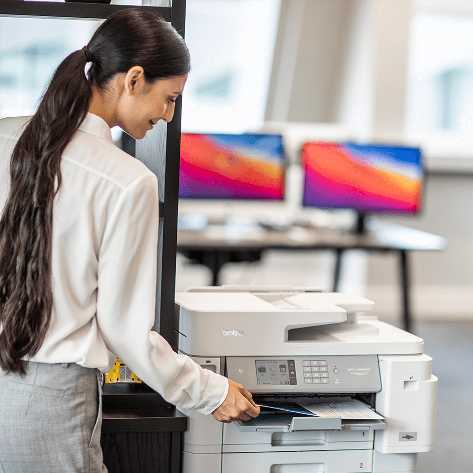 Woman in office picking up printed document