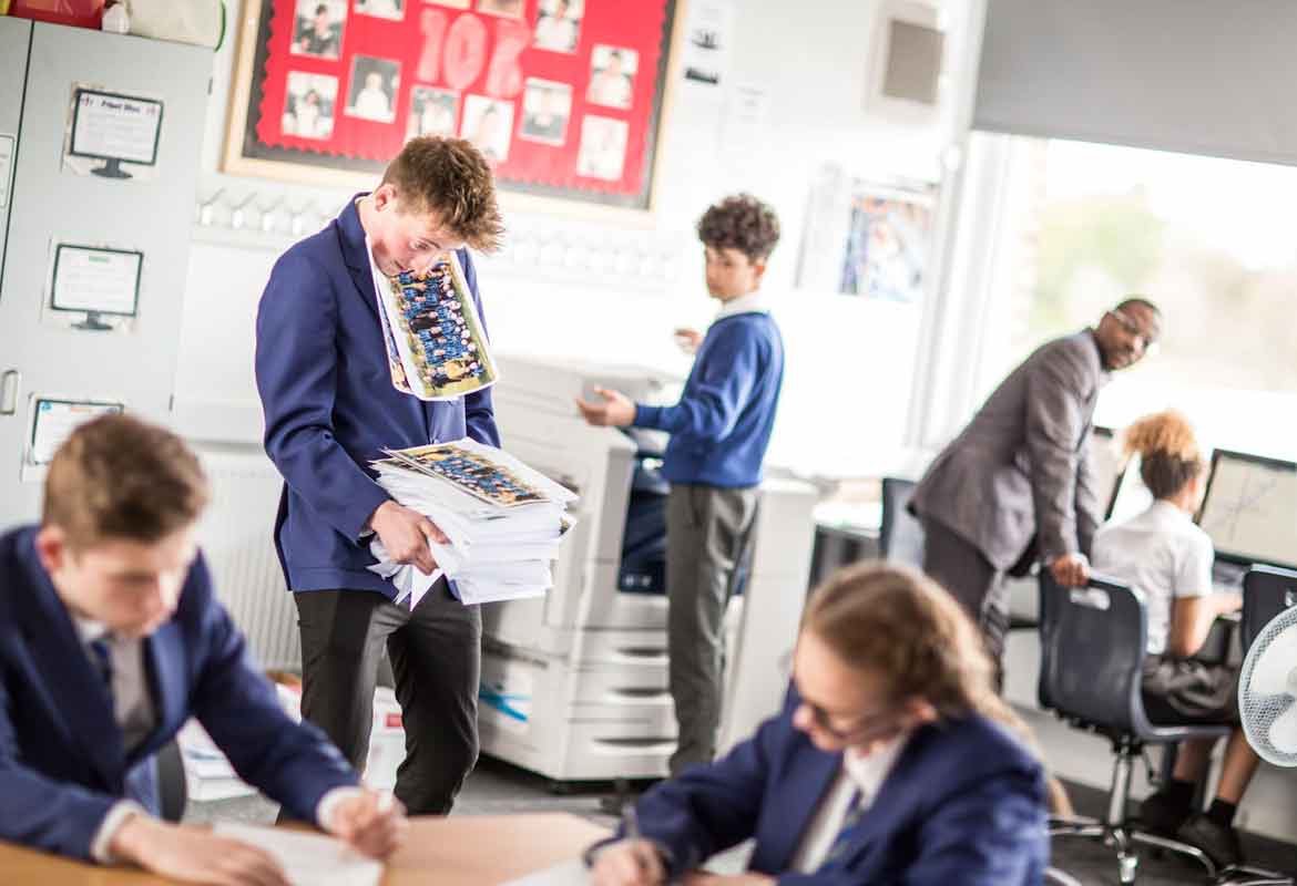 School children messing about in the classroom with lots of printouts