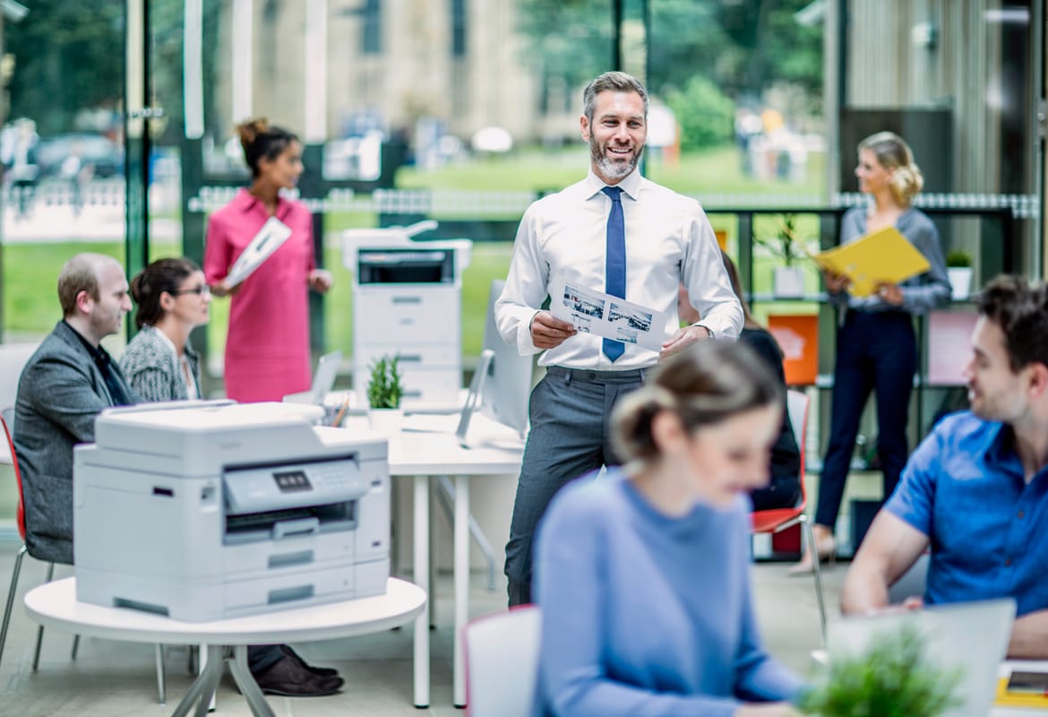 Brother printer in the foreground of a large busy office environment