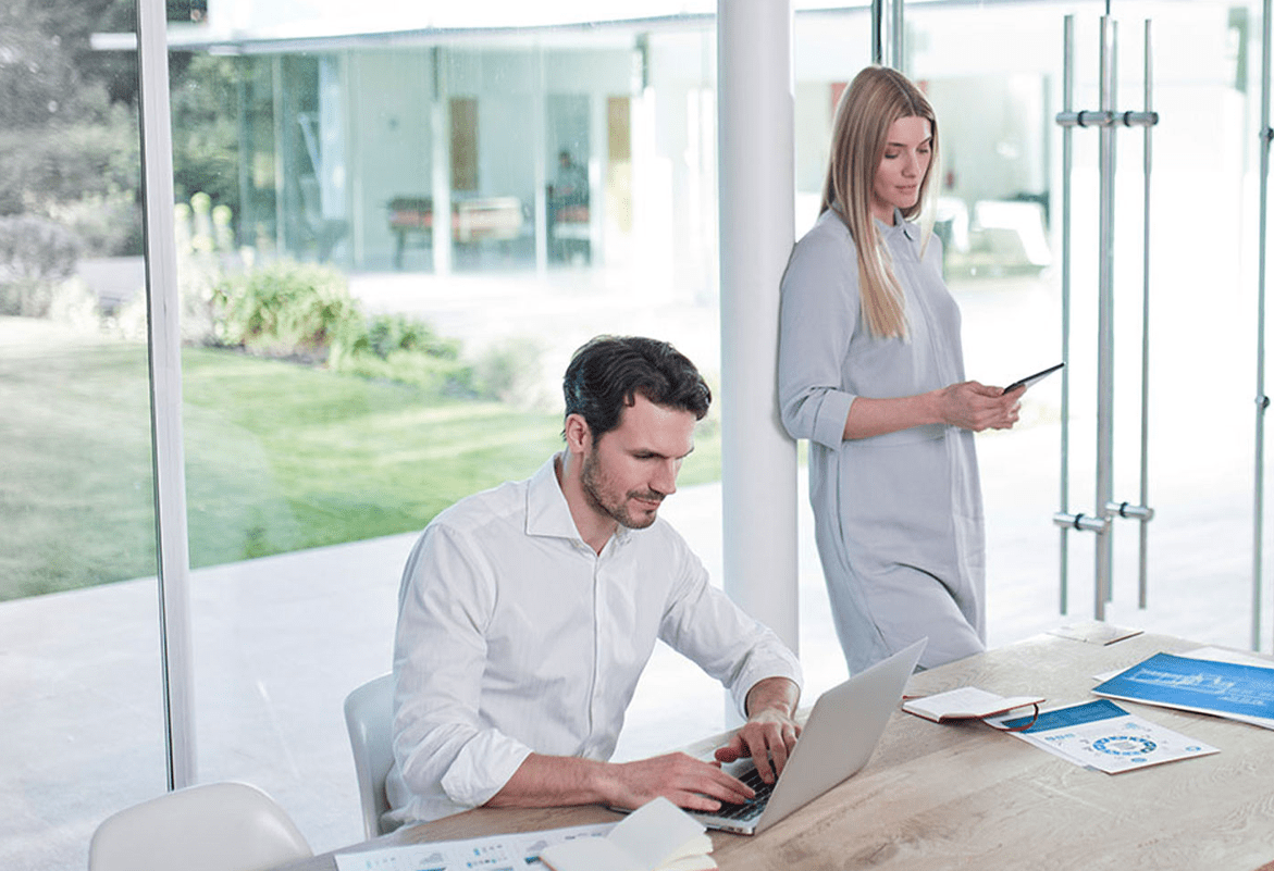 Woman and man in the office using laptop and mobile phone