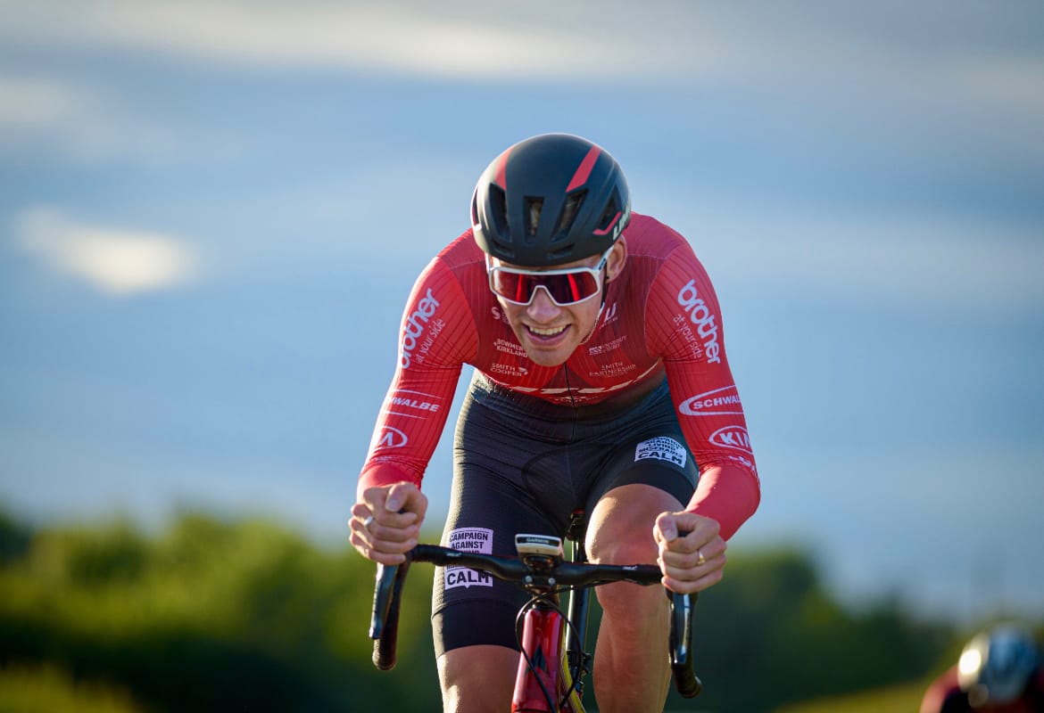 Joey Walker of Vitus Pro Cycling riding towards the camera in a 10-mile test at Cuckney with greenery and blue sky in the background